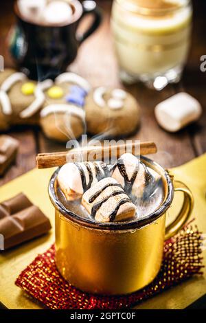 Heiße Schokolade mit Marschmalchen, Dampf oder Rauch, hausgemachtes Weihnachtsgetränk, mit Lebkuchenmann im Hintergrund Stockfoto