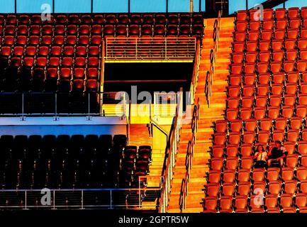 Zwei Einzelbesucher in einem Fußballstadion im Abendlicht Stockfoto