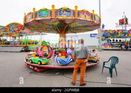 POZNAN, POLEN - 24. Jul 2017: Ein Mann, der vor einem bunten Karussell auf einem Jahrmarkt in der Gegend von Franowo steht. Stockfoto