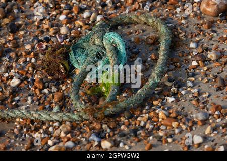 Stück weggeworfenes Seil und Plastikfischernetz am Strand gesehen. Stockfoto