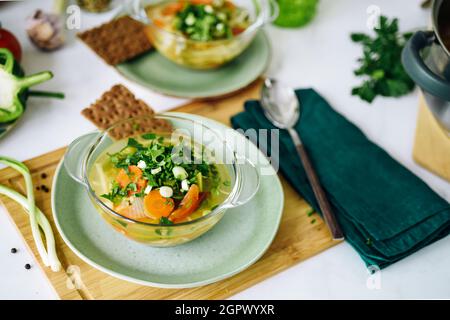 Zwei Teller mit veganem Essen, Kohlsuppe auf dem Tisch in der häuslichen Umgebung, die vegan gekochte Gerichte in einem grünen Gericht serviert, Draufsicht, Stockfoto