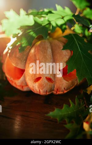 Halloween-Konzept: Kürbis und Blätter mit Punktlicht als Halloween-Party-Thema Hintergrund. Gruseliges Jack o'laternes Gesicht. Hochwertige vertikale Fotos Stockfoto