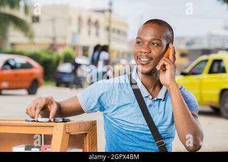 homme noir souriant assis à sa Cabine téléphonique Stockfoto