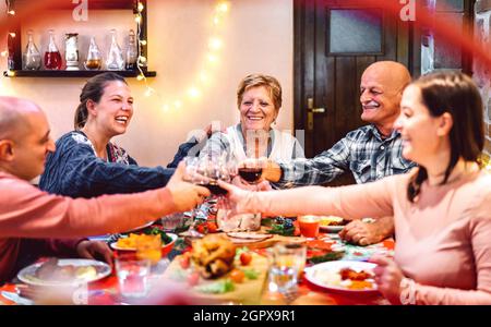 Leute toasting Rotwein und Spaß an den Winterferien Reunion - Dinner-Feier-Konzept mit glücklichen erwachsenen Freunden teilen Zeit zusammen zu Hause Stockfoto