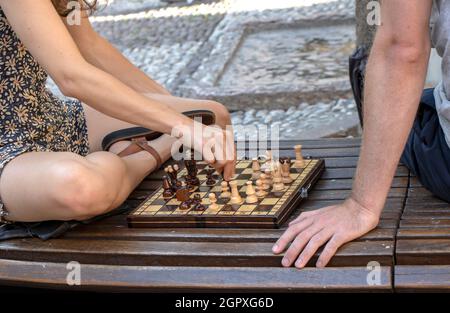 Junges Paar, das auf einer Parkbank in der Stadt Schach spielt Stockfoto