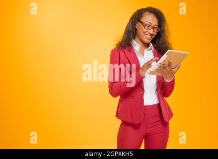 Jeune dame qui manipule une Tablette sous fond orange Stockfoto