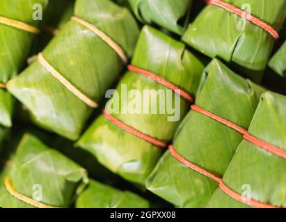 Khao tom - beliebtes laotisches und thailändisches Dessert. Gedämpfter klebriger Reis mit Füllung in Bananenblätter eingewickelt. Konzept der asiatischen Küche. Stockfoto