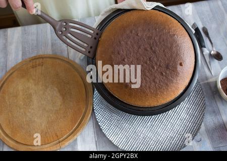 Schritt für Schritt der Prozess der Herstellung von Sauerrahm Pie Teig. Die Torte ist fertig. Weibliche Hände legen den gebackenen Teig auf eine Schüssel. Backkonzept. Stockfoto