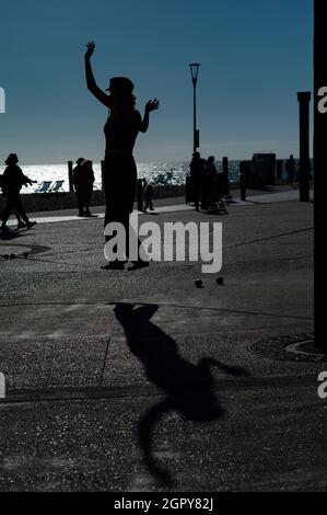 Silhouette einer jungen Frau, die auf einer schlaffen Linie am Meer in Brighton balanciert Stockfoto