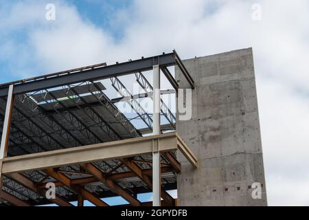 Eine große, mehrstöckige Metallwand mit Stahlträgern vor einem blauen Himmel. Die industrielle Struktur ist die Ecke eines Wolkenkratzers Stockfoto