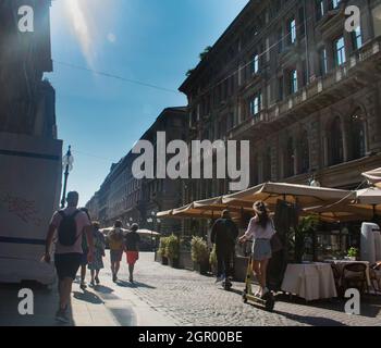 Paar auf Elektro-Scootern auf einer belebten Straße in Mailand, Italien. Geschäftsviertel Porto Nuovo. Umweltfreundliches Transportkonzept Stockfoto