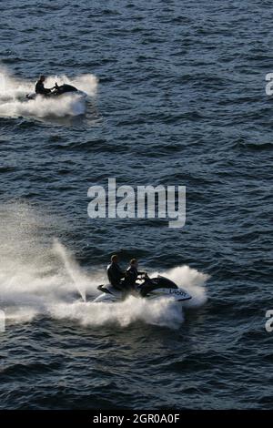 Firth of Clyde Scotland, Großbritannien 2005. Ein Jet-Ski surrt um die Caledonian MacBrayne Ferry auf der Caledonian Isle. Während es ein spektakuläres Spektakel war, wurde iit als hochgefährlich mit der Welle, die durch die Bugwelle des Schiffes verursacht wurde, eingestuft. Es ist ein kleines Jet-Propelled Fahrzeug, das über die Wasseroberfläche abrutscht und in der Regel wie ein Motorrad gefahren wird. Stockfoto