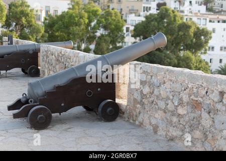 Aufnahme von zwei Kanonen auf einer mittelalterlichen Kathedrale auf einem Stadthintergrund in der Altstadt von Ibiza Stockfoto