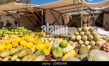 Melonen, Wassermelonen und Kürbisse, die am Boden verkauft werden, werden auf dem saisonalen Outdoor-Markt in Kyzyl-Orda, Kasachstan, Zentral- und Asien ausgestellt Stockfoto