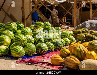 Melonen, Wassermelonen und Kürbisse, die am Boden verkauft werden, werden auf dem saisonalen Outdoor-Markt in Kyzyl-Orda, Kasachstan, Zentral- und Asien ausgestellt Stockfoto