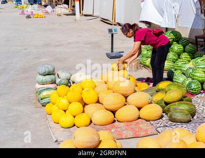 Kasachische Frau, die Kürbisse, Melonen und Wassermelonen am Boden auf dem saisonalen Outdoor-Markt in Kyzyl-Orda, Kasachstan, Zentral- und Asien verkauft Stockfoto