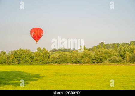 Der jungfräuliche Heißluftballon, der von einem Feld in der Nähe von Glastonbury Somerset aufsteigt. In der Nähe des Sonnenuntergangs Stockfoto