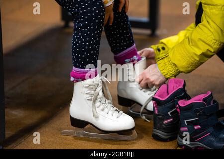 Familie in Winter Park. Mutter mit Tochter in einem Ice Arena. Mama legt ihre Tochter in Skates Stockfoto