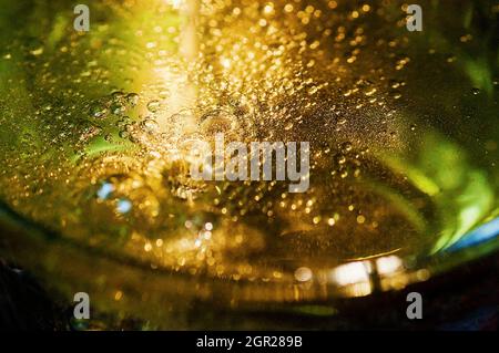 Luxuriöse goldene Schaumwein-Blasen in grüner Flasche, Detail Stockfoto