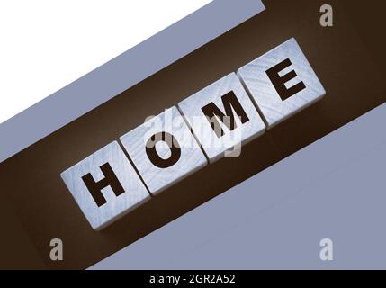 Holzwürfel mit dem Wort Home, Heimat auf schwarzem Hintergrund. Immobiliengeschäft oder Auswanderung consept. Stockfoto