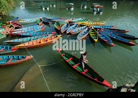 POKHARA - NEPAL, 30. MAI 2016: Ein Bootsmann tritt auf den sitzt in seinem Boot in dem See von Fewa Stockfoto