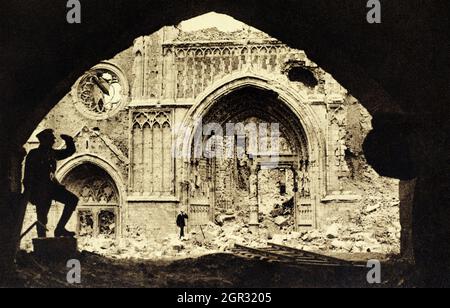 Eine historische Ansicht eines britischen Soldaten, der über die Trümmer vor dem devistierten Eingangstor der Ypern Cathedral blickt, die während des Ersten Weltkriegs durch einen Beschuss schwer beschädigt wurde. Aufgenommen im Jahr 1918. Was wie ein Stück leichte Eisenbahnstrecke aussieht, kann man im rechten vorderen Bereich sehen. Stockfoto