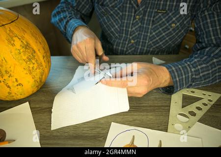 Jack O'Lantern zu Hause machen. Jack O'Lantern Thread-Vorlage erstellen Prozess. Der Mann bereitet den Kürbis zum Schnitzen vor. Stockfoto