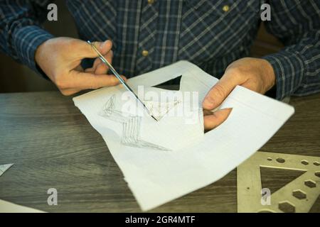 Jack O'Lantern zu Hause machen. Jack O'Lantern Thread-Vorlage erstellen Prozess. Der Mann bereitet den Kürbis zum Schnitzen vor. Stockfoto