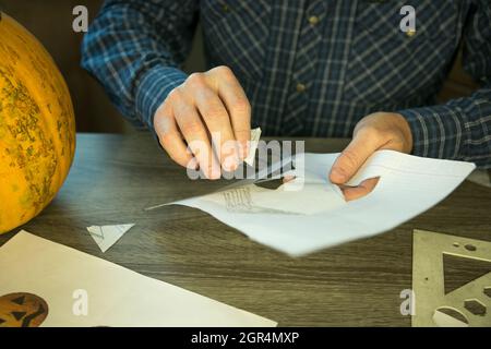 Jack O'Lantern zu Hause machen. Jack O'Lantern Thread-Vorlage erstellen Prozess. Der Mann bereitet den Kürbis zum Schnitzen vor. Stockfoto