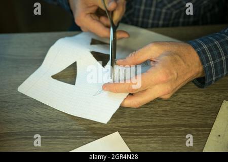 Jack O'Lantern zu Hause machen. Jack O'Lantern Thread-Vorlage erstellen Prozess. Der Mann bereitet den Kürbis zum Schnitzen vor. Stockfoto