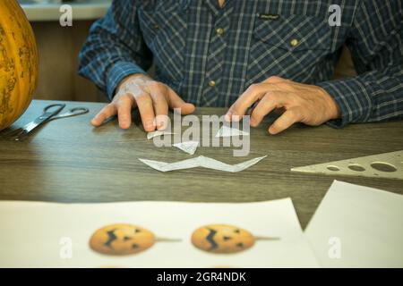 Jack O'Lantern zu Hause machen. Jack O'Lantern Thread-Vorlage erstellen Prozess. Der Mann bereitet den Kürbis zum Schnitzen vor. Stockfoto