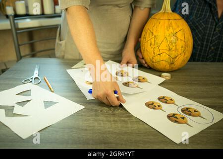 Halloween. Jack O'Lantern zu Hause machen. Jack O'Lantern Thread-Vorlage erstellen Prozess. Eine Frau bereitet den Kürbis zum Schnitzen vor. Stockfoto