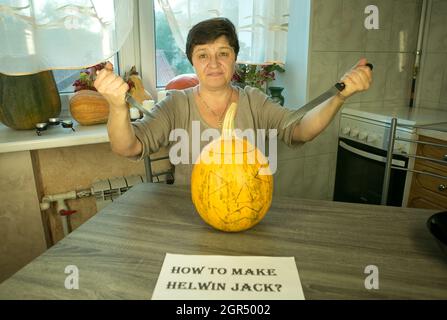 Jack O'Lantern zu Hause machen. Jack O'Lantern Thread-Vorlage erstellen Prozess. Eine Frau bereitet den Kürbis zum Schnitzen vor. Die Frau ist glücklich mit dem Stockfoto