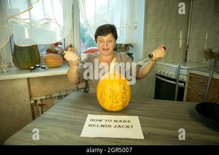 Jack O'Lantern zu Hause machen. Jack O'Lantern Thread-Vorlage erstellen Prozess. Eine Frau bereitet den Kürbis zum Schnitzen vor. Die Frau ist glücklich mit dem Stockfoto