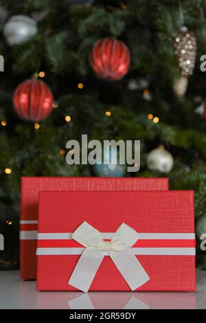 Weihnachtsgeschenke.Überraschungen und Geschenke für die Winterferien. Rote Boxen auf Weihnachtsbaum Hintergrund.Weihnachten und Neujahr. Stockfoto