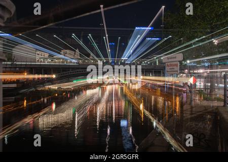 Berlin Deutschland - August 25 2017; von Bäumen gesäumte Boulevards entlang der Spree mit städtischen Nachtlichtern, die sich in ruhigem Wasser unter der Eisenbahnbrücke widerspiegeln Stockfoto