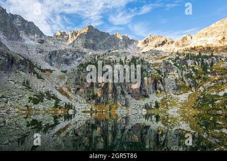 Ruhiger Morgen an einem alpinen See bei Sonnenaufgang mit zerklüfteten Gipfeln und einer Reflexion in den Rocky Mountains, Colorado, USA Stockfoto