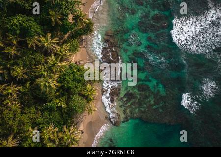 Drohnenaufnahme eines sonnigen Tages, der wunderschön einige Felsen an der Küste des Strandes von Punta Uva in Limon, Costa Rica, stürzt Stockfoto