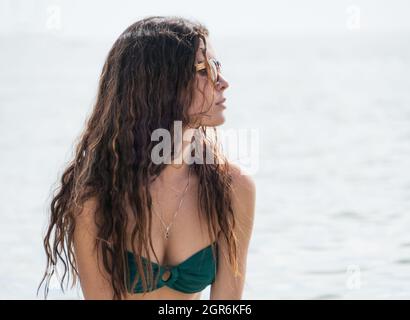 Attraktive junge hispanische Frau mit Bikini und Sonnenbrille am Strand Stockfoto