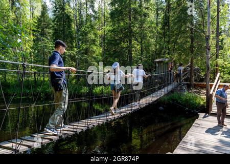 Ruskeala, Russland - 10. Juli 2021: Menschen überqueren die Hängebrücke über den Wasserfall Ruskeala am Fluss Tohmajoki in der Republik Karelien in Russ Stockfoto