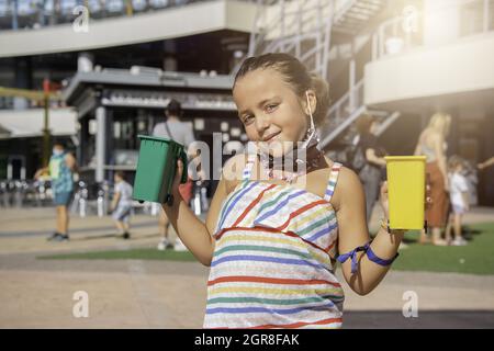 Kaukasisches Mädchen, das lächelnde grüne und gelbe Mülltonnen zeigt. Stockfoto