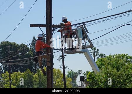 Los Angeles, CA / USA - 29. April 2021: Es wird gezeigt, dass tagsüber Elektroleitungen Telekommunikationskabel entlang von Telefonleitungen aufrüsten. Stockfoto