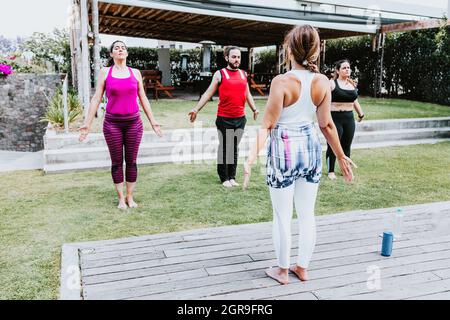 Junge lateinamerikaner im Yoga-Kurs machen Atemübungen mit einem Lehrer im Freien in Mexiko-Stadt Stockfoto
