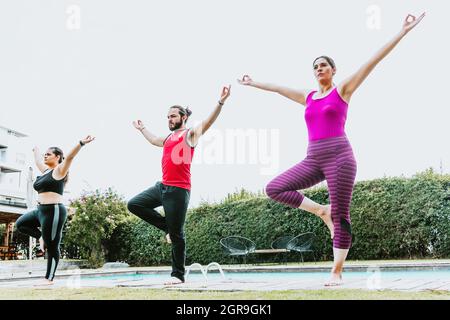 Gruppe von lateinern, die Yoga-Haltungen praktizieren, stehen in Lateinamerika im Freien Stockfoto