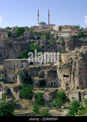 Ländliche Stadt des traditionellen Landes in der Türkei Moschee von Guzelyurt und Felsen geschnitten Höhlenhäuser in den typischen vulkanischen Felsen von Kappadokien geschnitzt Stockfoto