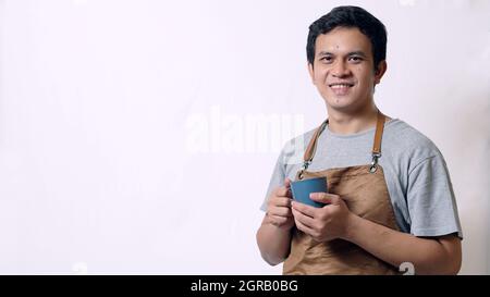 Asian Mann Trägt Schürze Trinken Kaffee Stockfoto