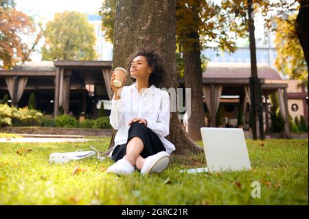 Eine nette junge Frau, die Zeit im Park verbringt und zufrieden aussieht Stockfoto