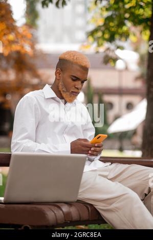 Schöner und eleganter junger Mann mit Smartphone Stockfoto