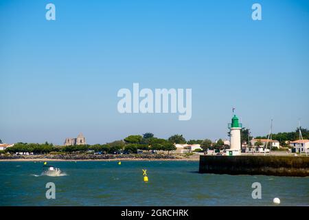 Leuchtturm La Flotte mit einem Ausflugsboot auf dem Meer und l' Abbaye des Châteliers im Hintergrund an einem sonnigen Sommertag Stockfoto