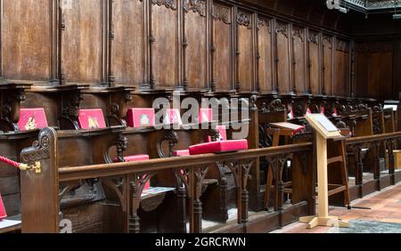 Reihe von geschnitzten hölzernen Mercy-Sitzen, Mönche sitzen einen Teil der Misericorde im Great Quire im Christchurch Priory UK Stockfoto